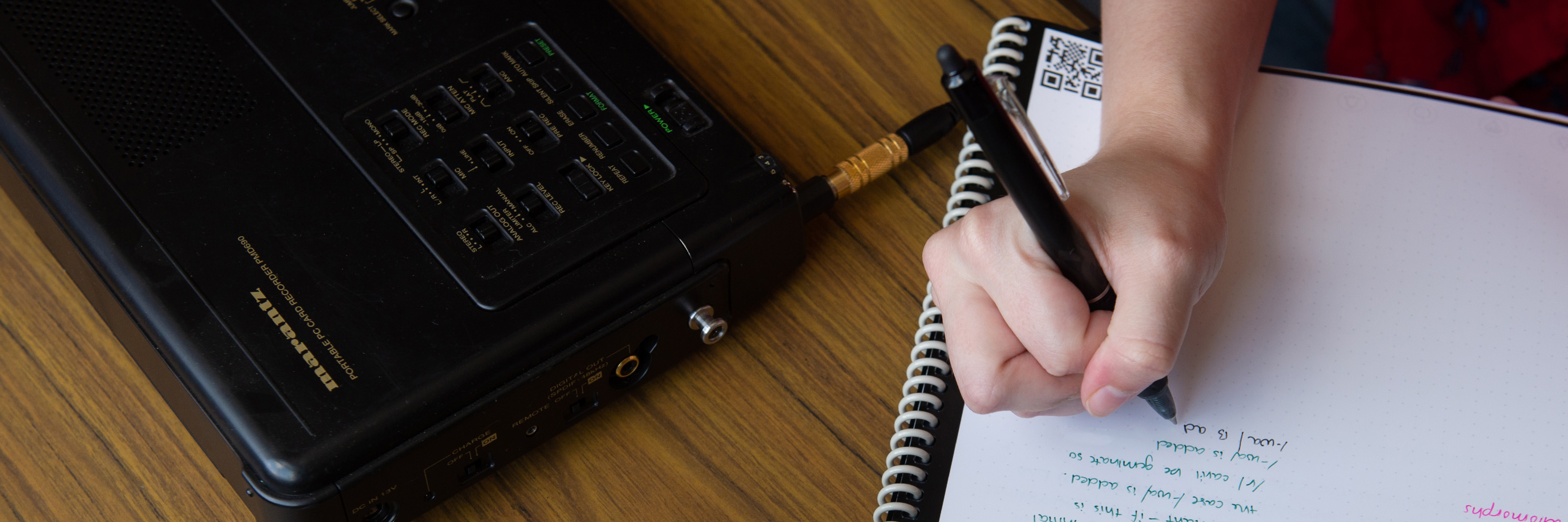 Closeup shot of portable recorder and person writing in notebook